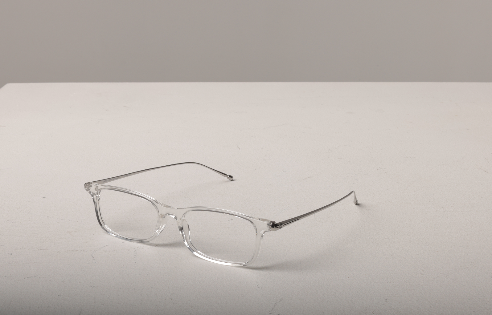 Front view of ultra-slim clear frame reading glasses with lightweight titanium temples on a white surface.