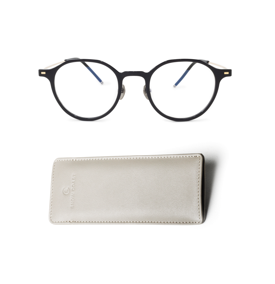 A pair of round, black-framed eyeglasses sits above a light gray leather case on a white background.
