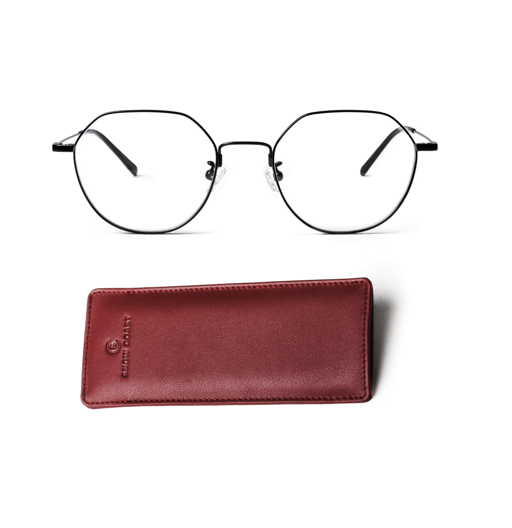 A pair of black, thin-framed octagonal glasses above a reddish-brown leather case on a white background.