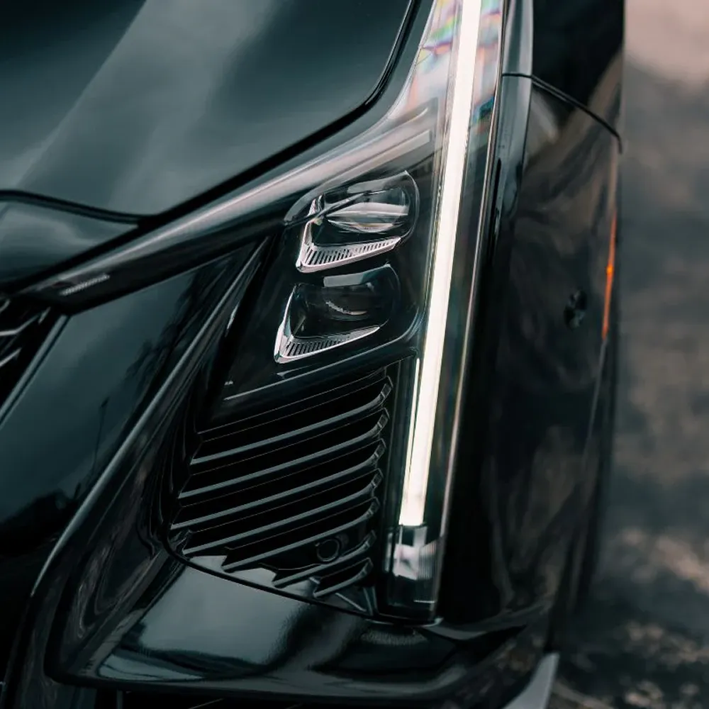 A close-up view of the headlight and grille on a modern, glossy black car.