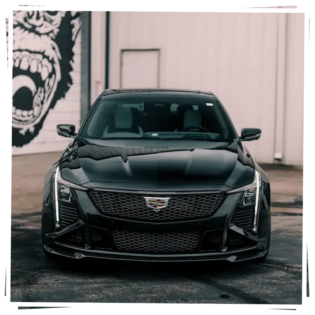 A black Cadillac sedan is parked in front of a building with a large gorilla mural.