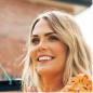 Smiling person outdoors with blurred background.
