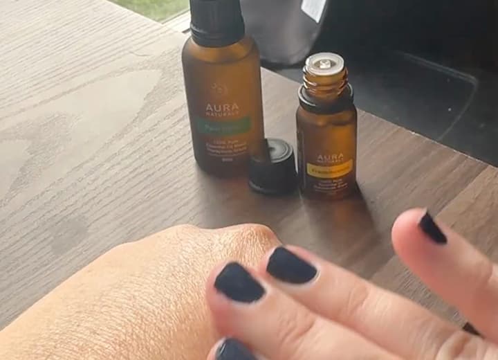 Hand applying oil from bottles on a wooden table.