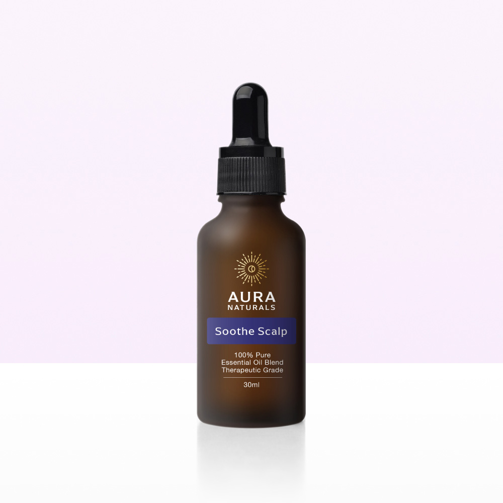 A brown dropper bottle of Aura Naturals Soothe Scalp essential oil blend on a reflective surface.