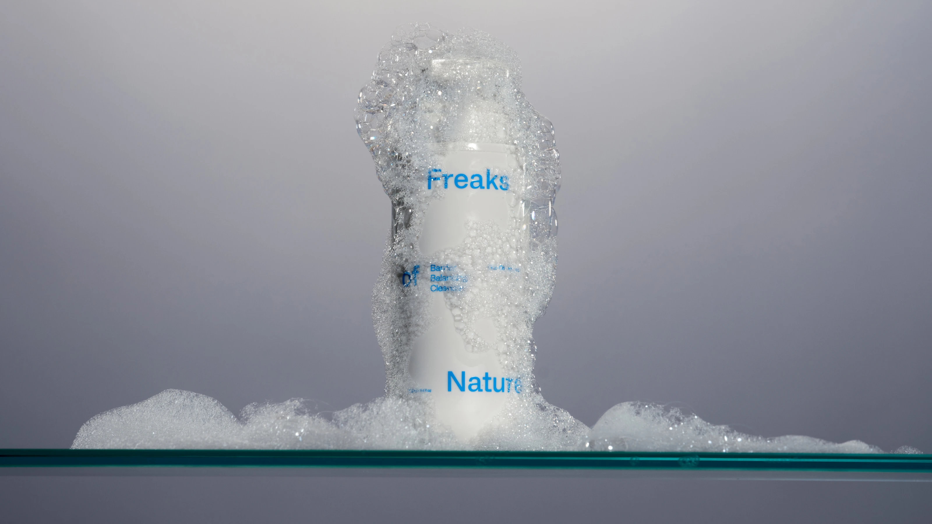 White bottle covered in bubbles on a glass surface.