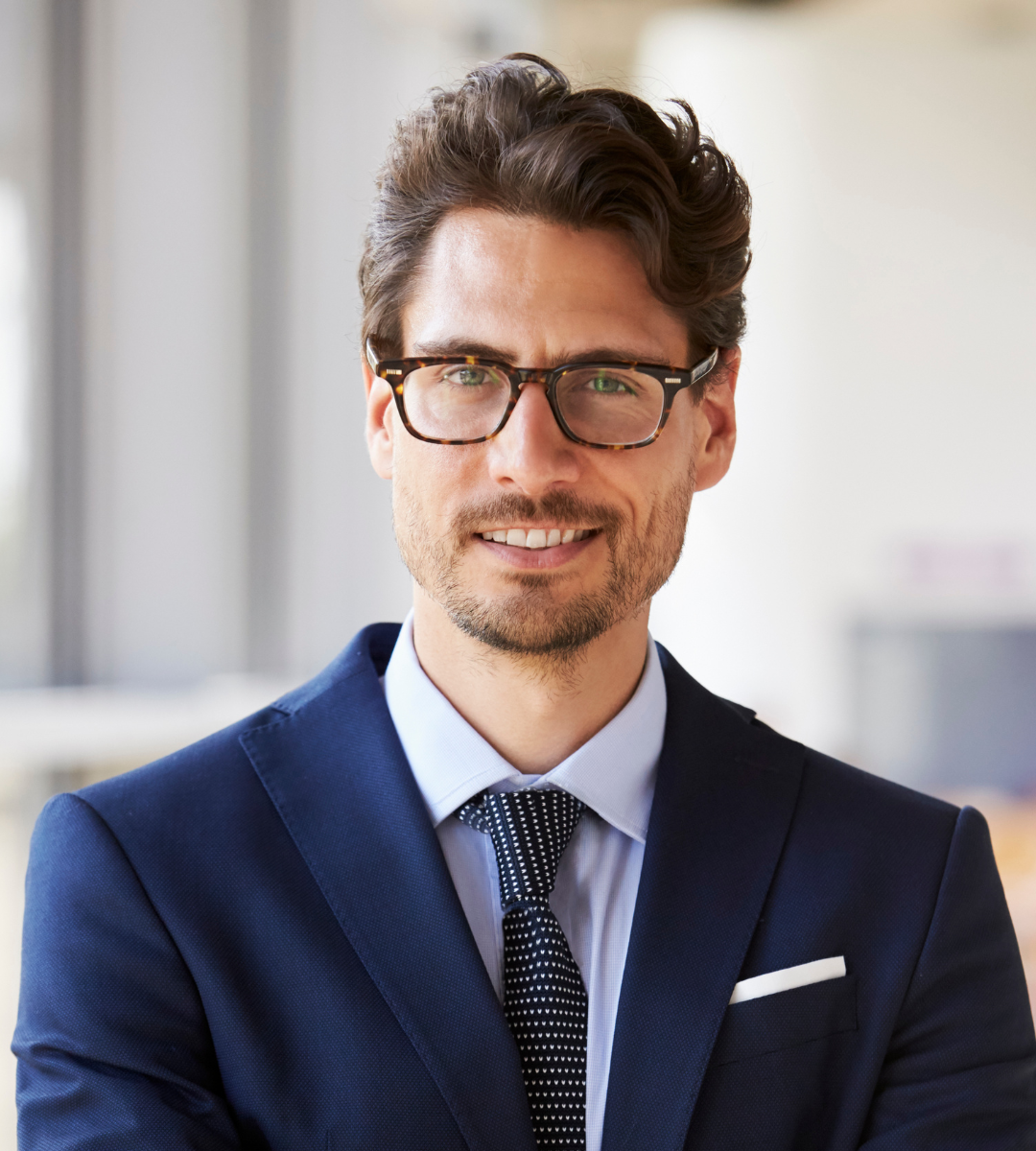 Man in a suit and glasses smiling indoors.