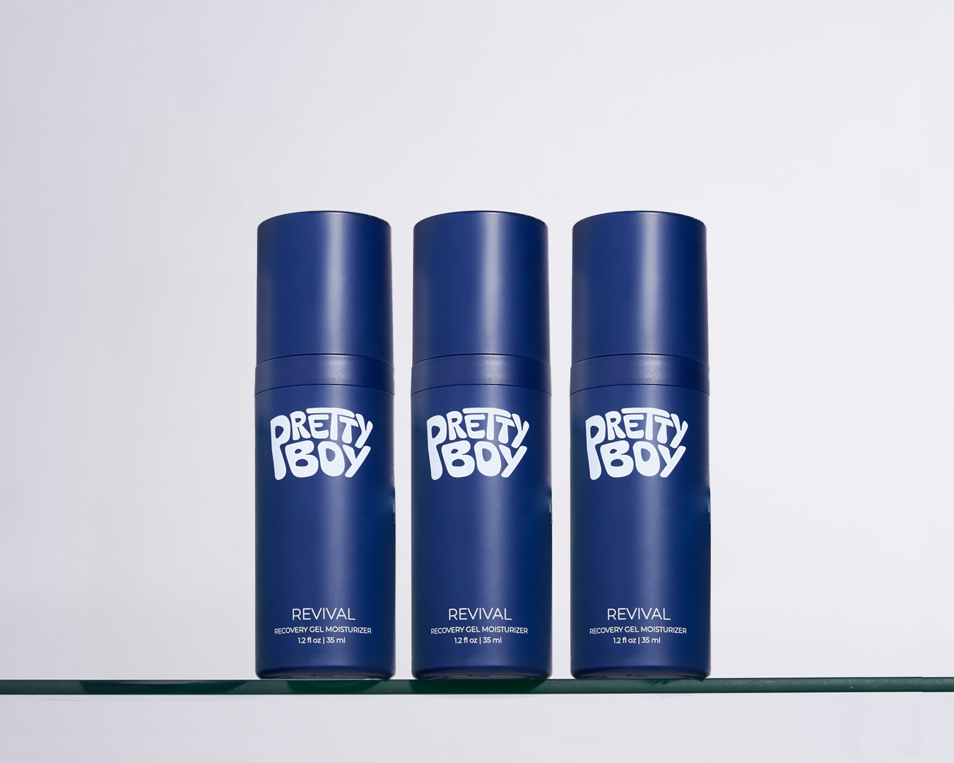 Three blue bottles labeled 'Pretty Boy' on a glass shelf.