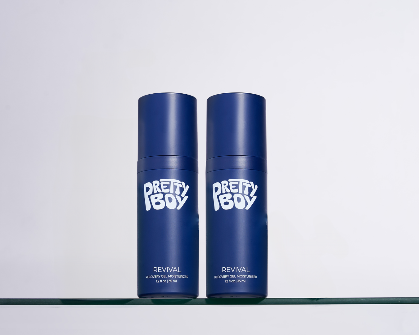Two blue bottles labeled 'Pretty Boy' on a glass shelf.