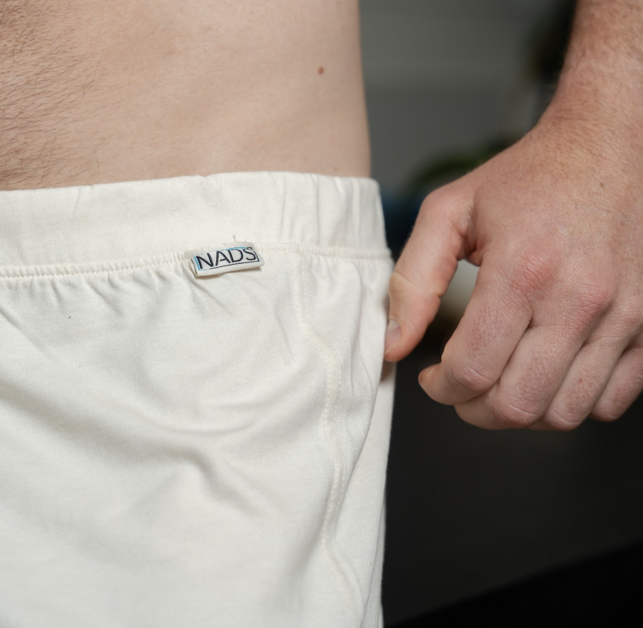 Close-up of a person wearing white shorts with a 'NADS' label.