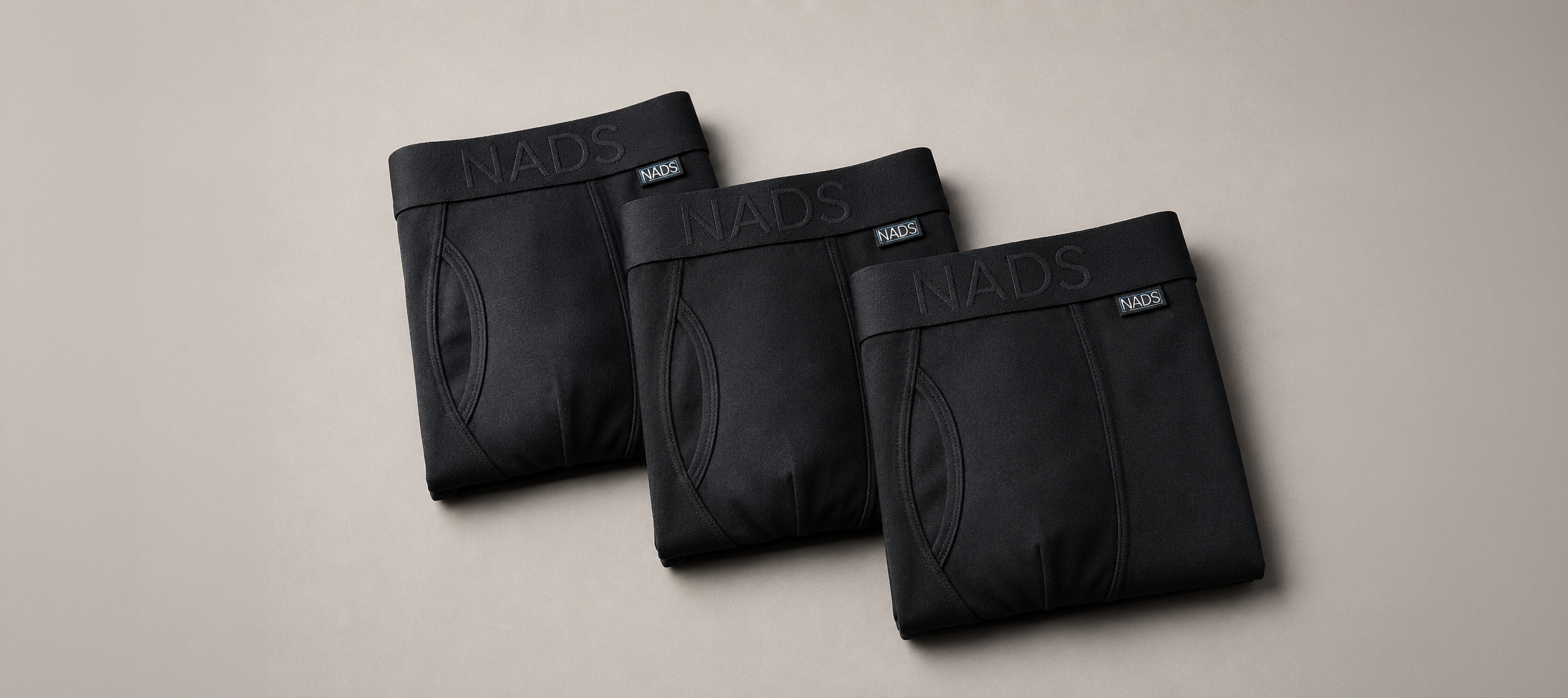 Three pairs of folded black NADS boxer briefs arranged diagonally on a plain background.