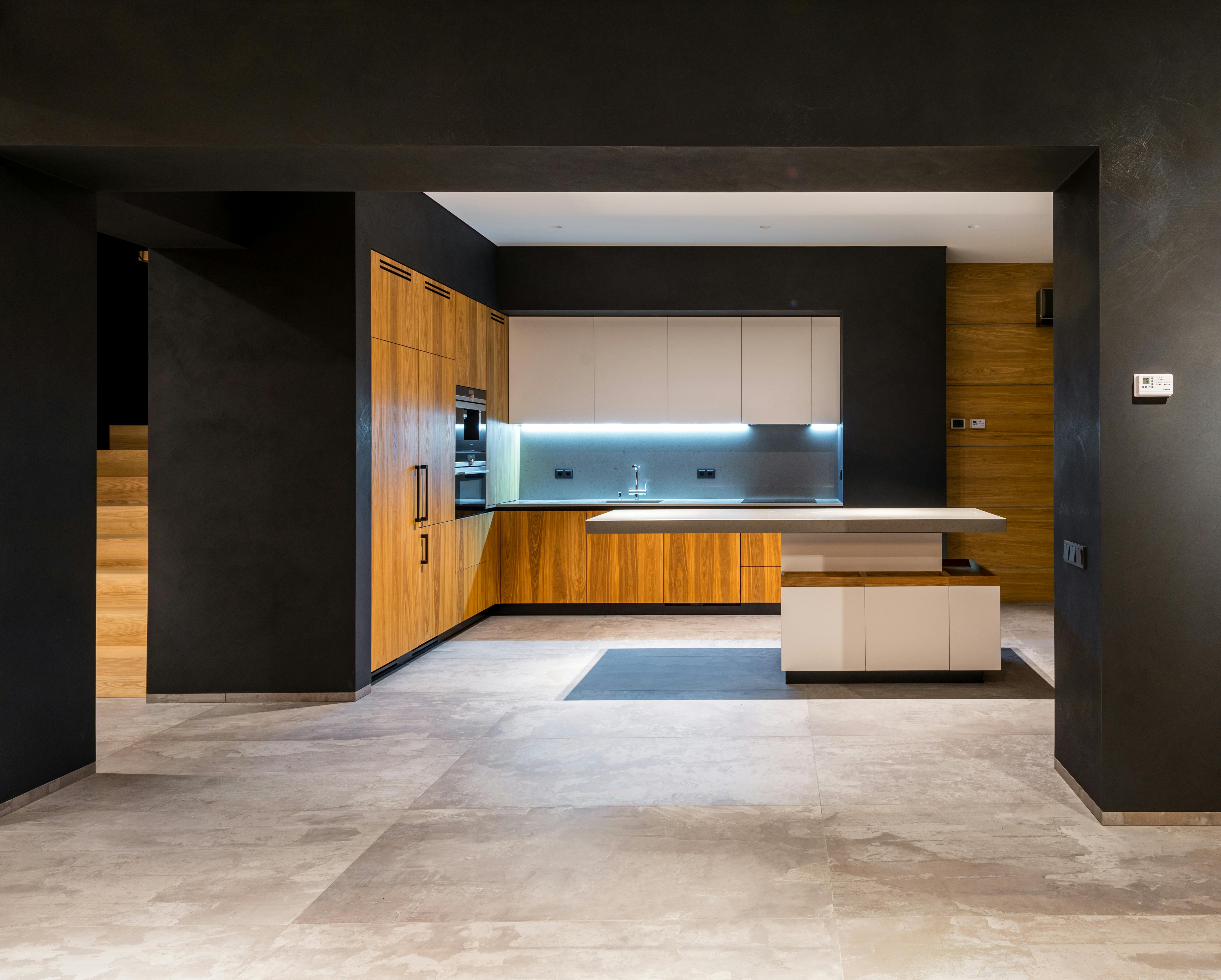 Modern kitchen with wooden cabinets, island, and dark walls.