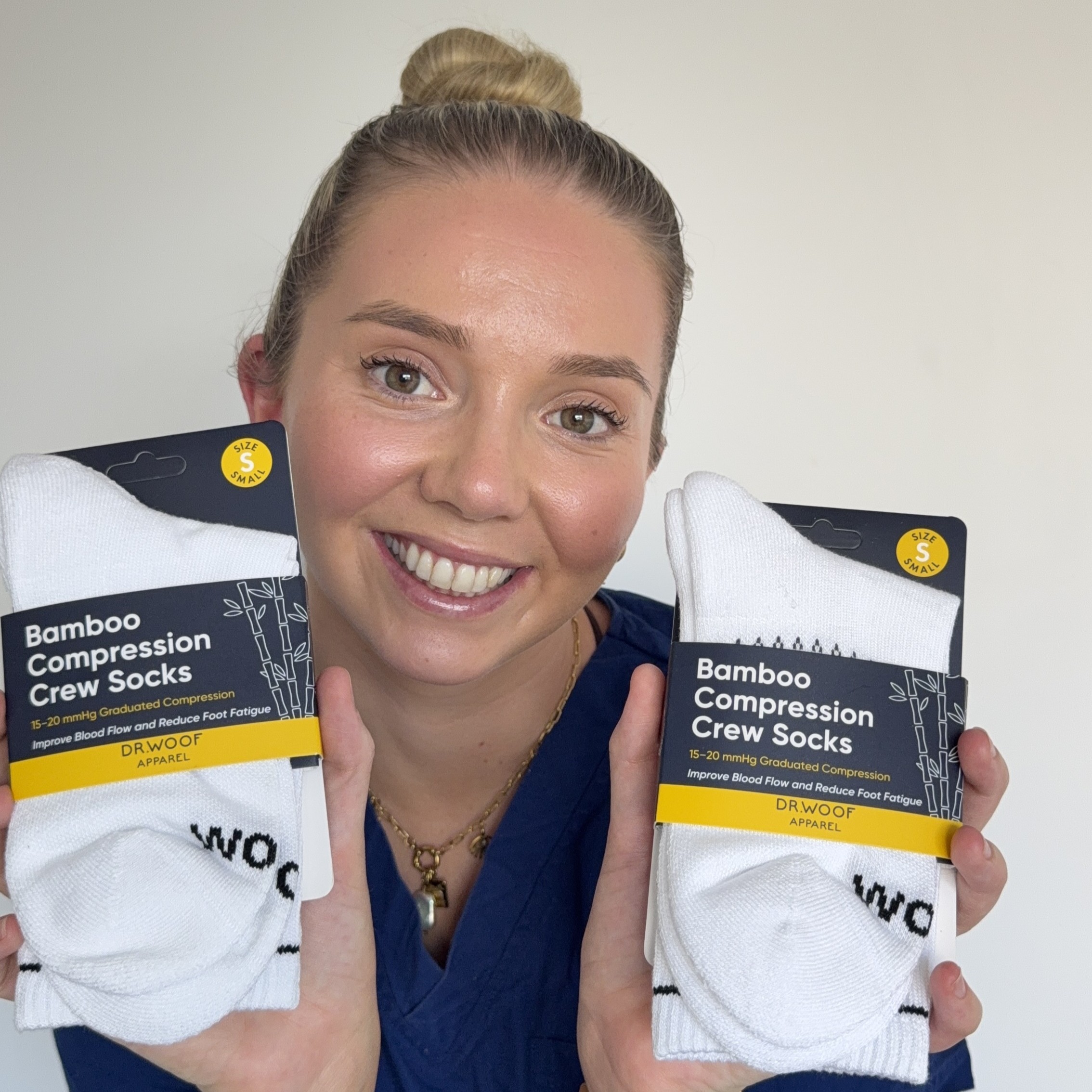 Smiling customer holding two packs of white bamboo compression crew socks
