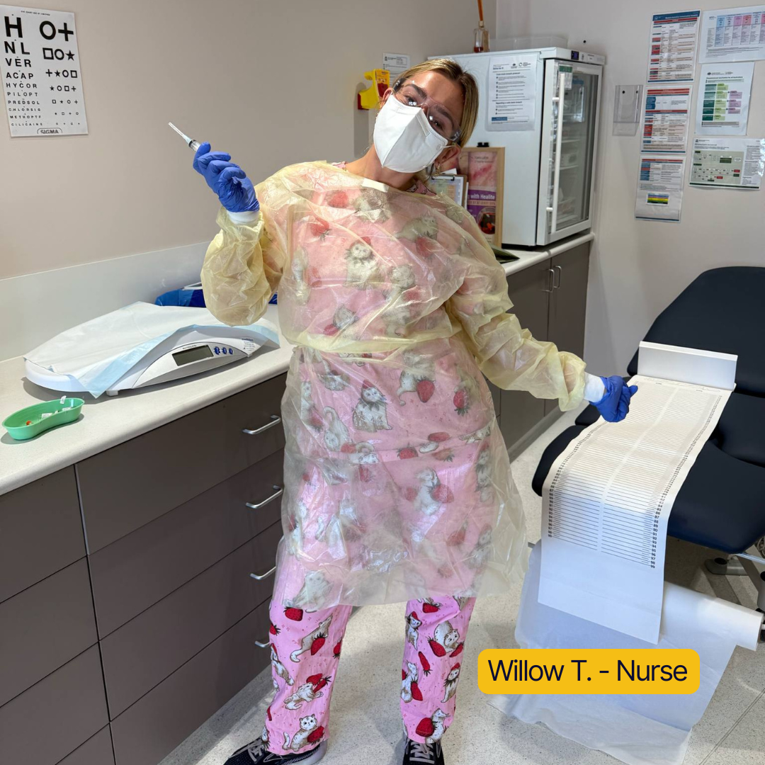 Person in protective gear holding a syringe in a medical room.