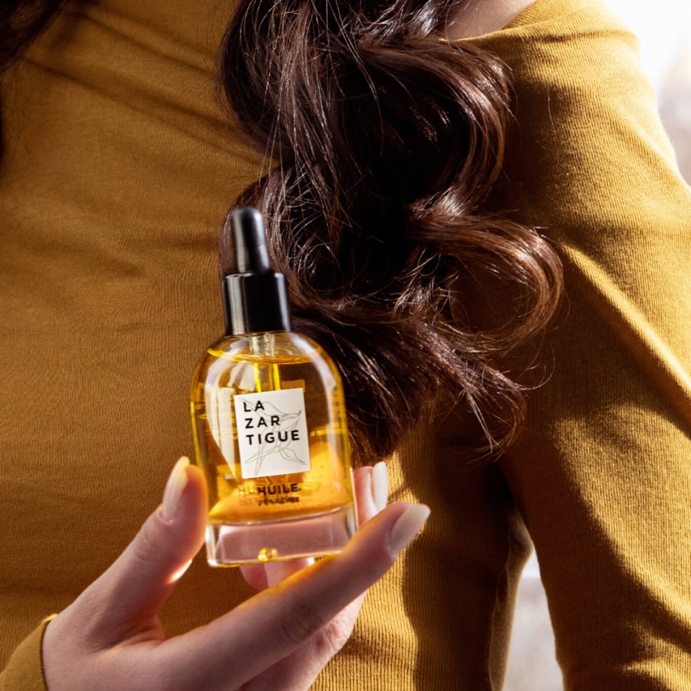 Person holding a bottle of La Zartigue hair oil.