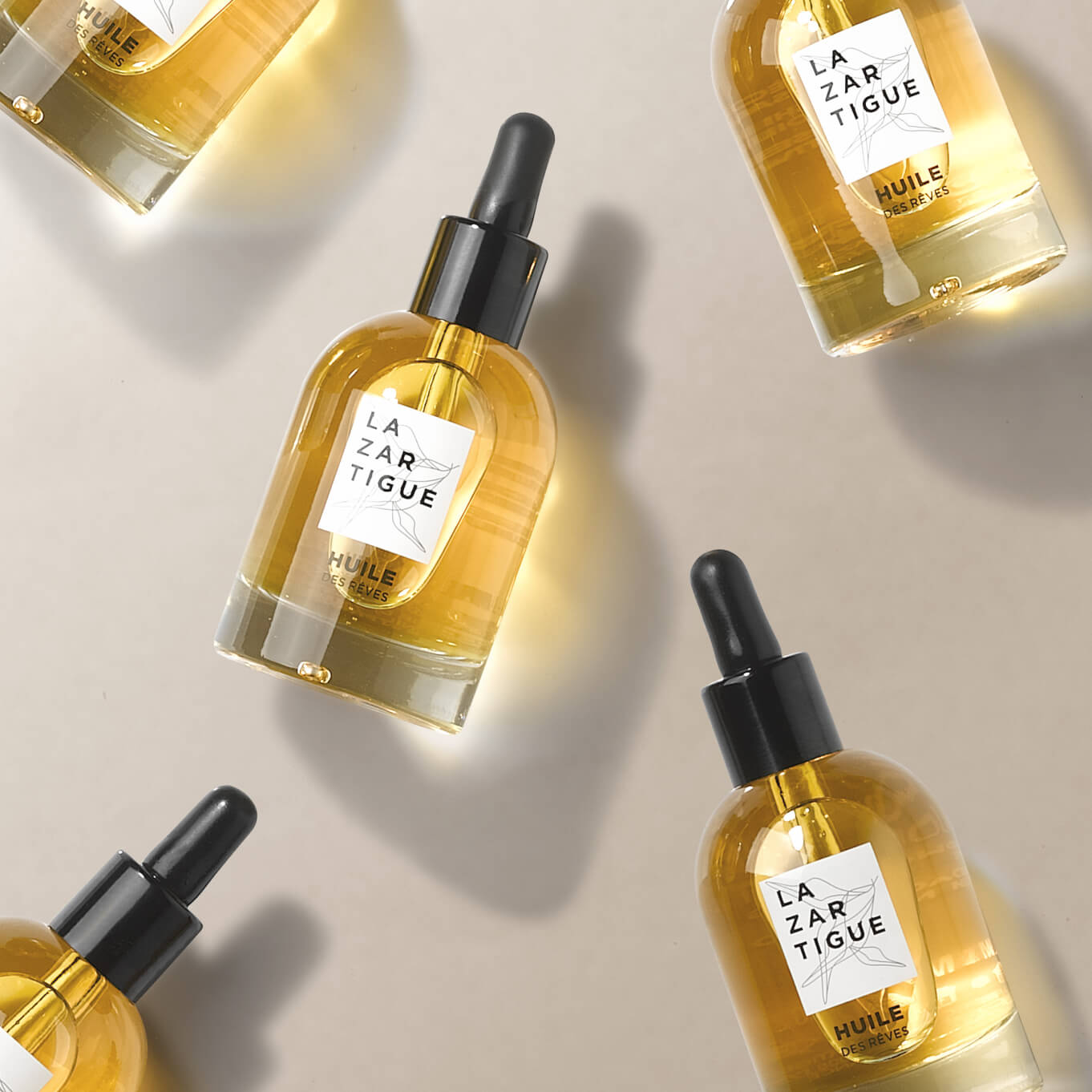 Several bottles of yellow oil with black droppers on a light background.