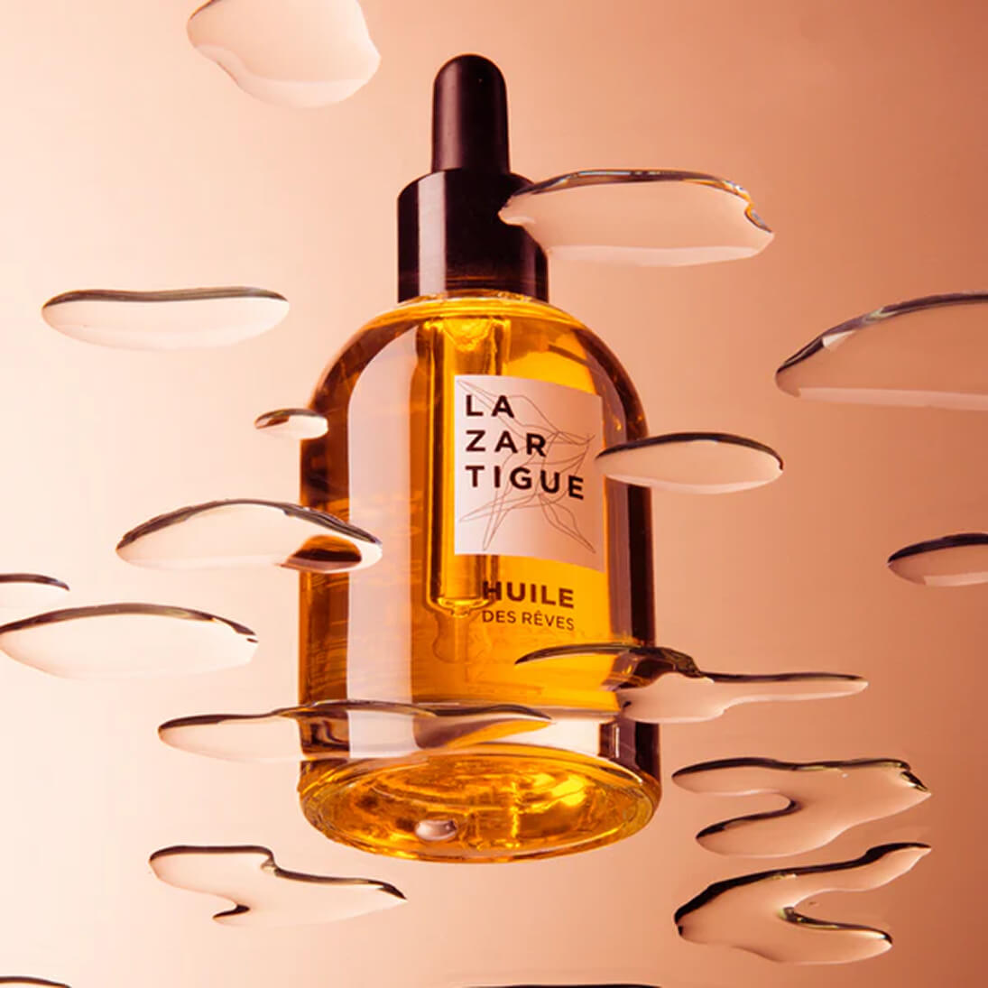 A bottle of La Zartigue oil with liquid droplets around it.