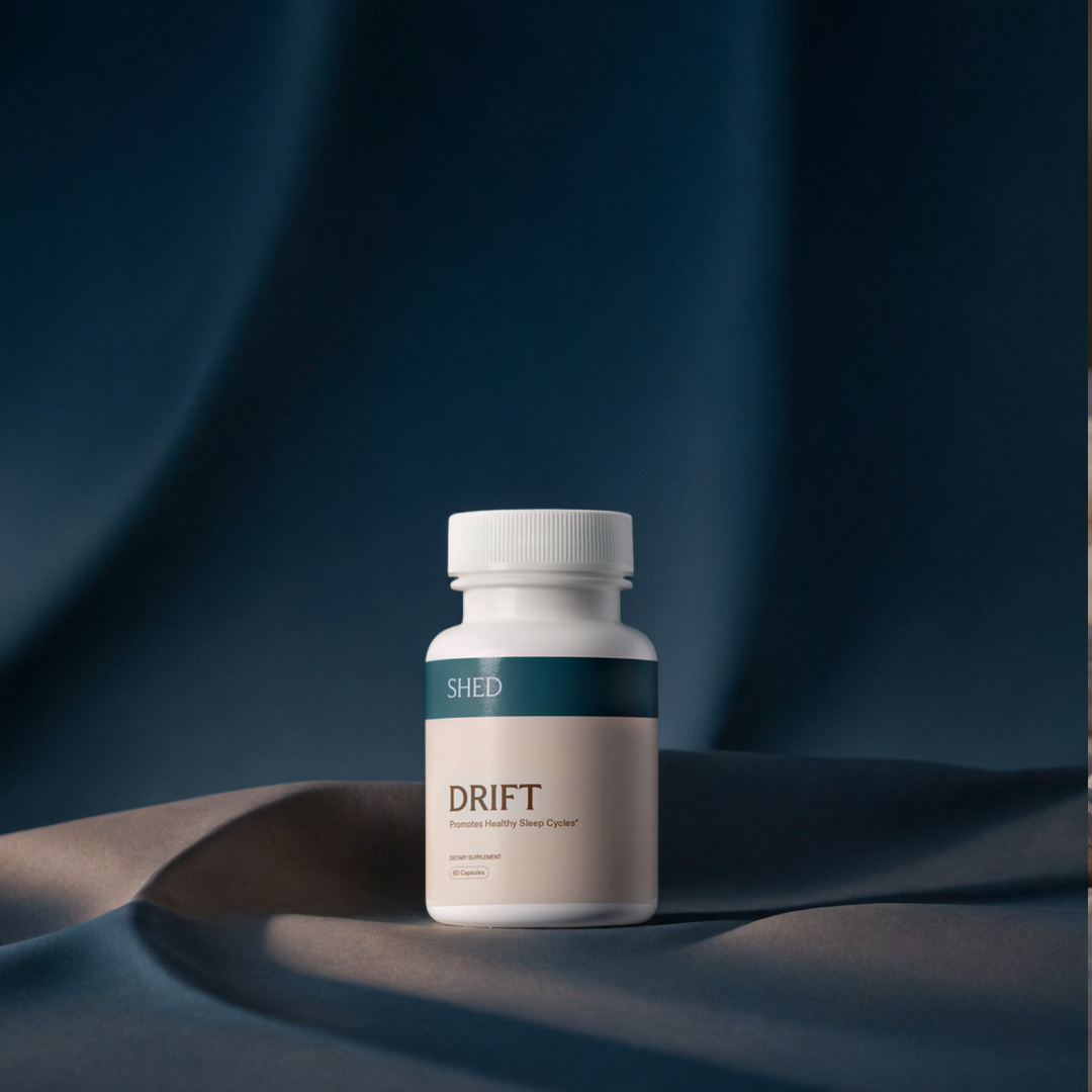 White bottle labeled 'DRIFT' on a dark, draped fabric background.