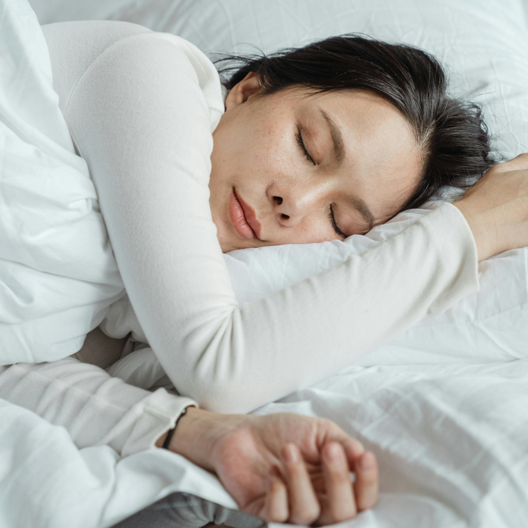 Person sleeping peacefully on a white bed.