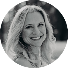 Black and white photo of a smiling person with long hair in a circular frame.