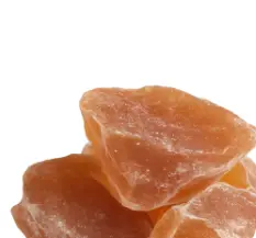 A close-up of several rough, orange-colored, translucent rocks piled together against a white background.