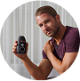 Person holding a small electronic device with a circular screen.