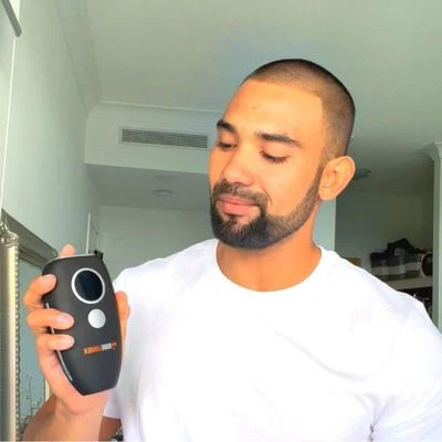 Person holding a black electronic device in a room.
