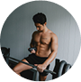 Man in gym holding a phone, standing near weights.