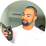 Man holding a black electronic device, standing indoors.