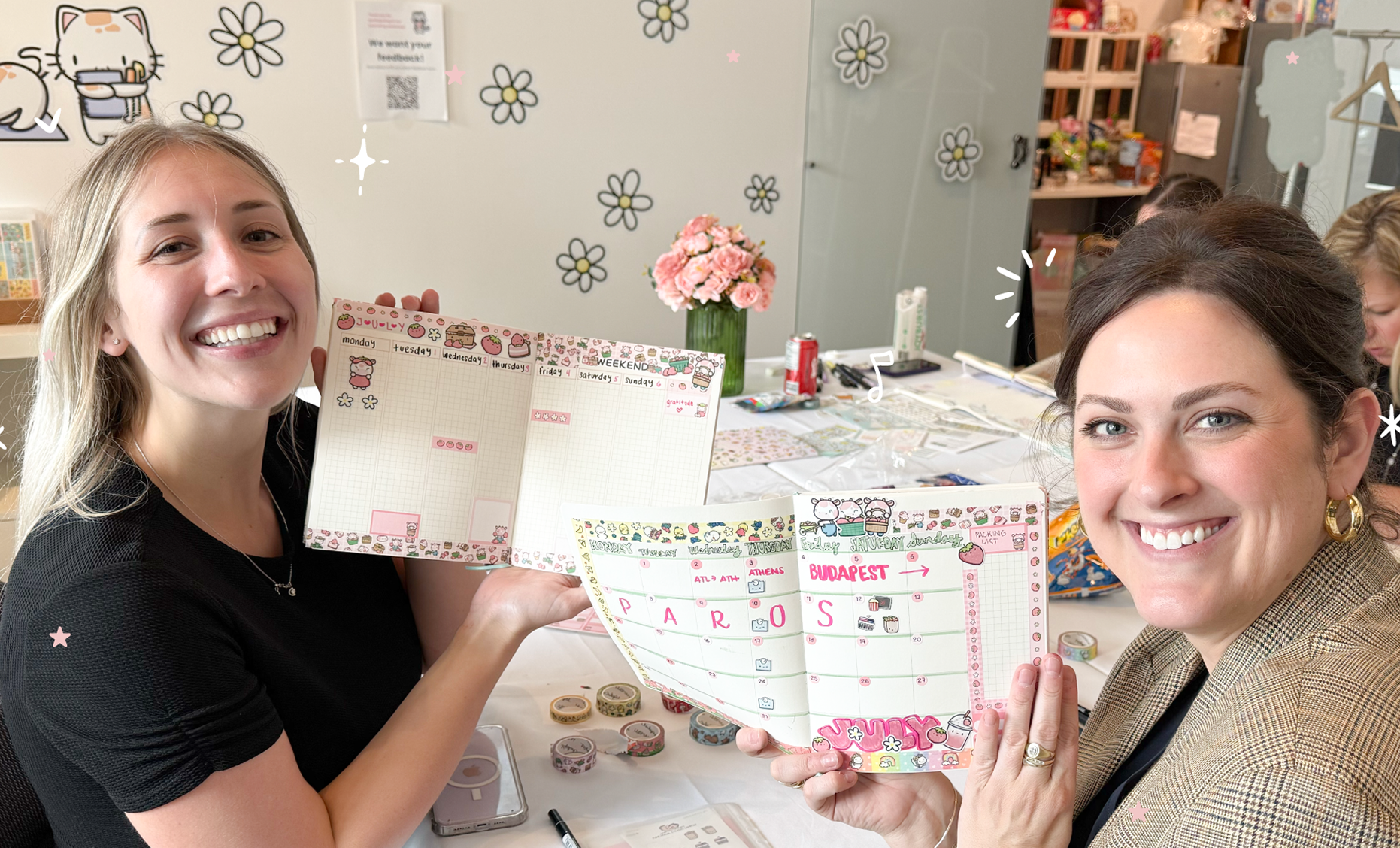 Two people holding decorative planners with cartoon designs, smiling at the camera.