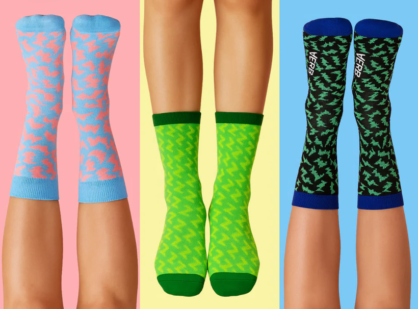 Three pairs of colorful patterned socks on legs against pastel backgrounds.