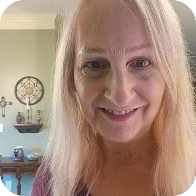 Person with long blonde hair smiling indoors.