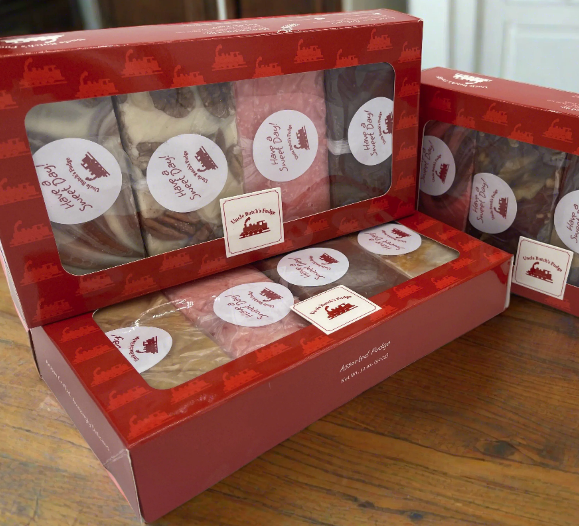 Boxes of assorted fudge with red packaging on a wooden table.