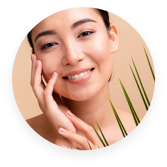 Smiling person touching their face with green leaves nearby.