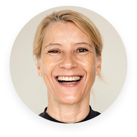 A smiling person with light hair in a circular frame.