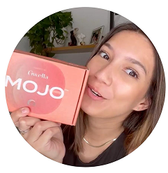 Person holding a box labeled 'MOJO' with a plant in the background.