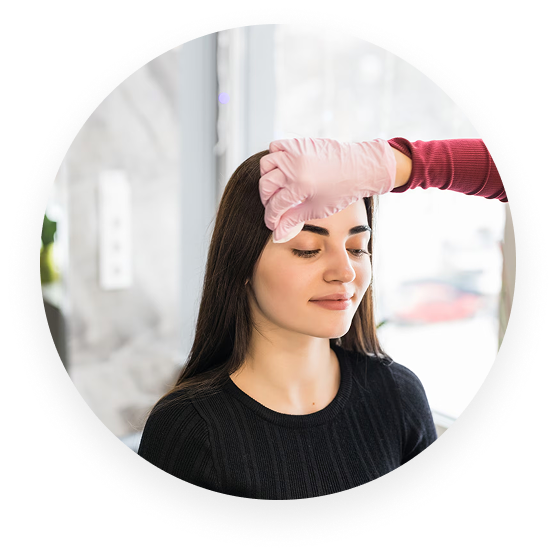 Person in a salon receiving an eyebrow treatment with gloved hands.