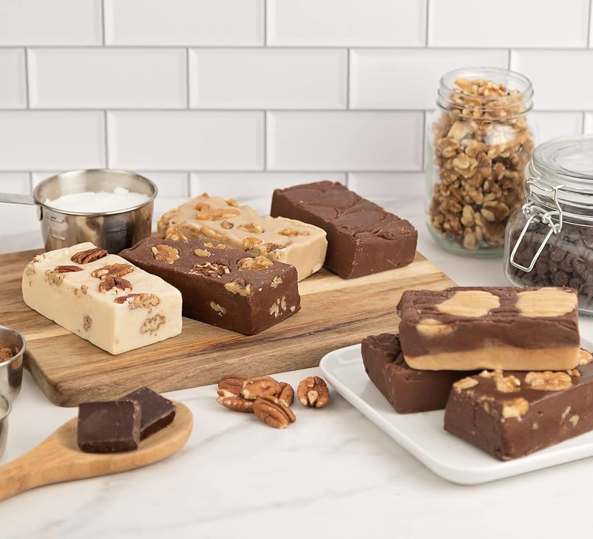 Assorted fudge blocks with nuts on a wooden board and white plate.