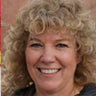 Smiling woman with curly hair outdoors.