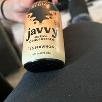 A hand holding a bottle of Javvy coffee concentrate.