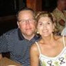 A man and woman sitting closely, smiling at the camera.