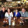 Four people sitting at a restaurant table with drinks.