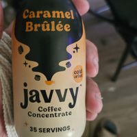 Hand holding a bottle of Javvy Caramel Brûlée coffee concentrate.