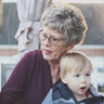 Older woman holding a young child outdoors.