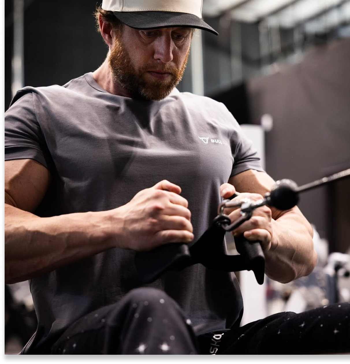 Man in a gym using a cable machine for exercise.