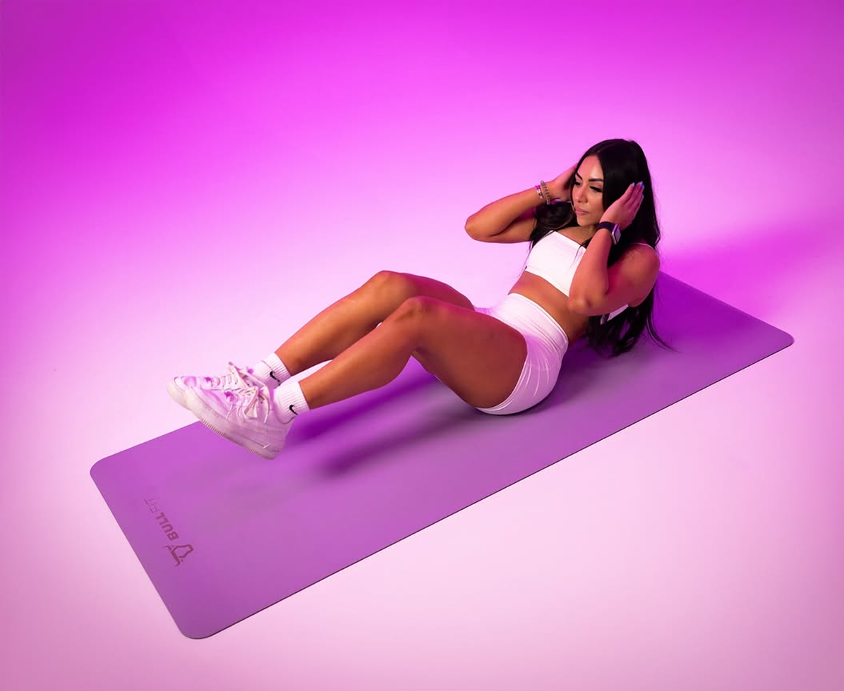 Person exercising on a yoga mat with a purple background.