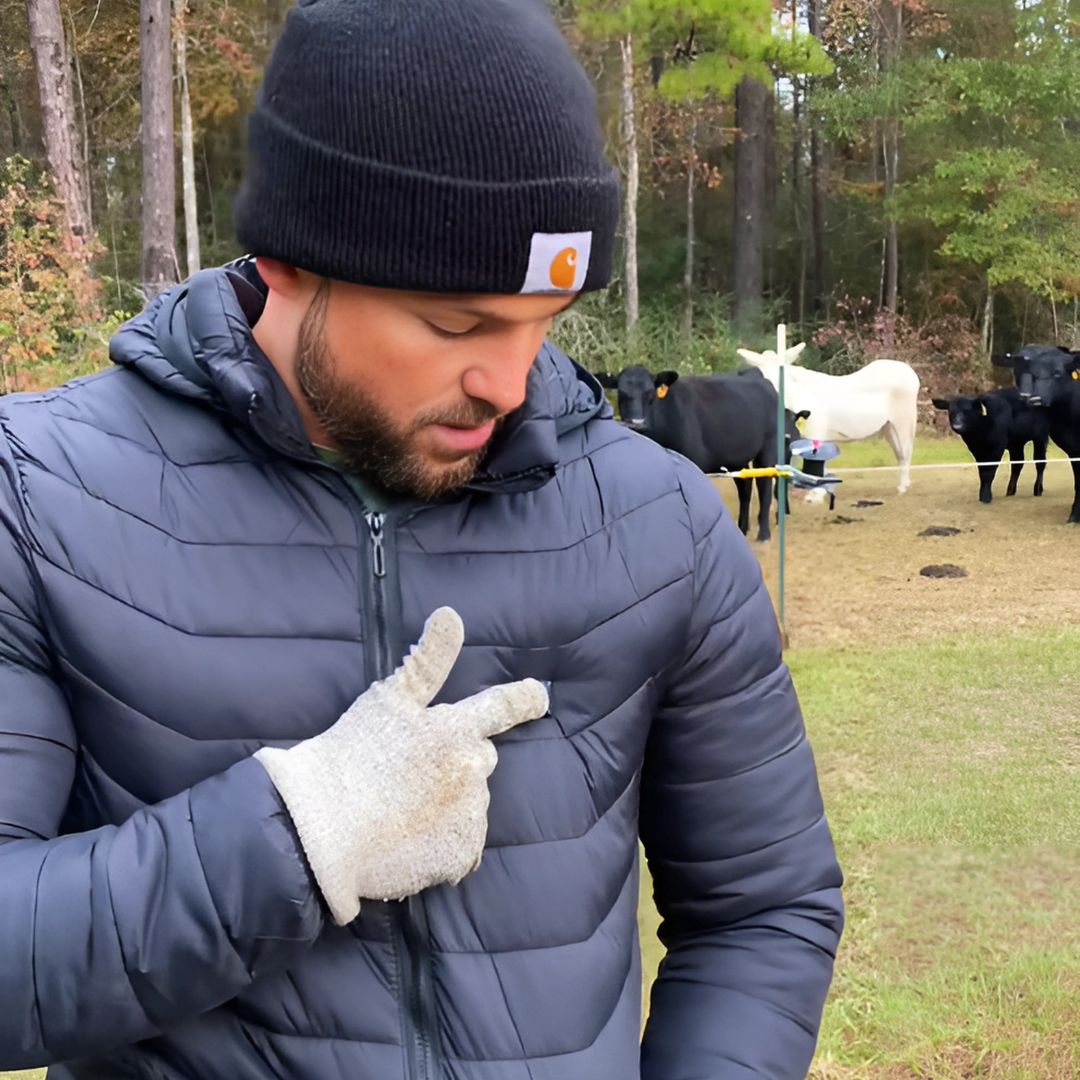 Person in winter clothing outdoors with cows in the background.