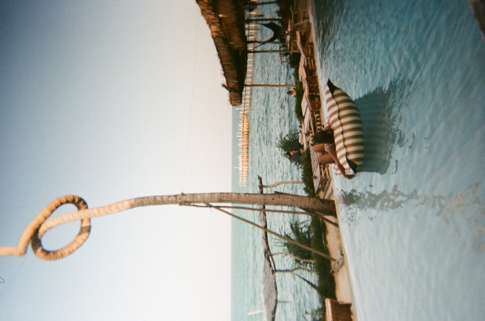 Person relaxing on a striped float in a pool by the ocean.