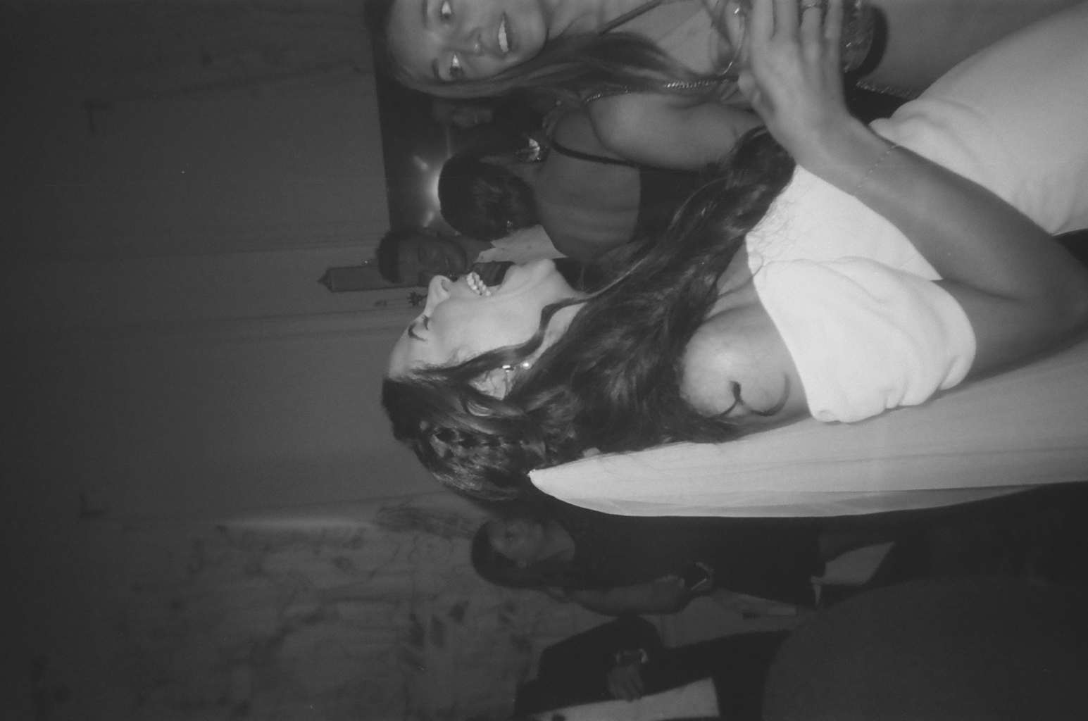 Black and white photo of a woman laughing at a party.