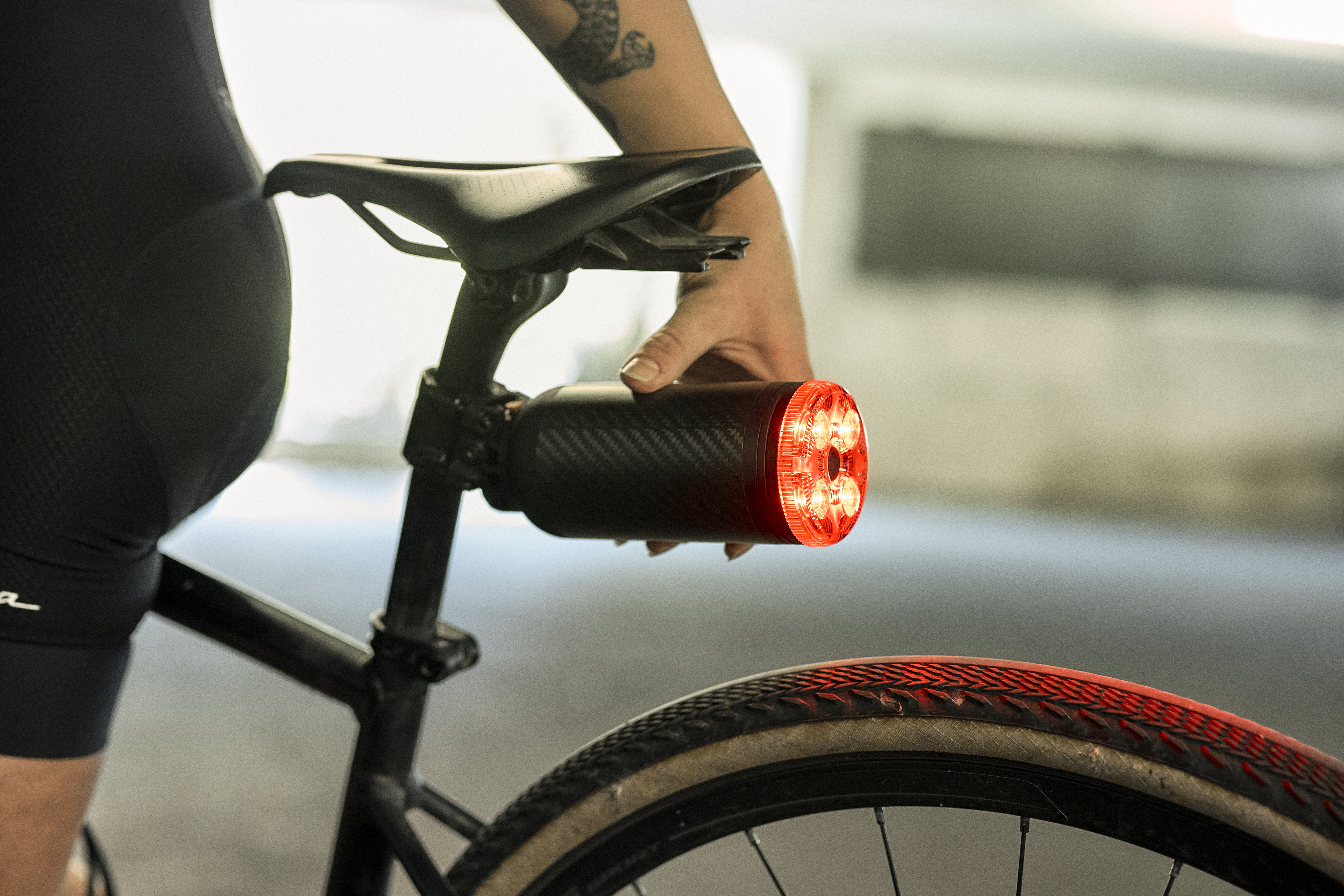 Person attaching a rear light to a bicycle seat.
