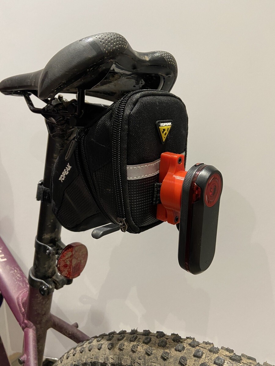 Bicycle seat with black bag and red rear light attached.
